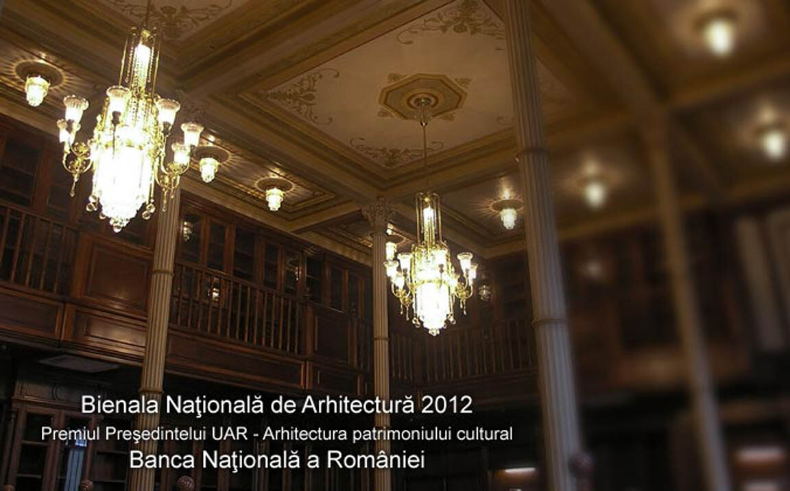 A tall hall in the Palace of the National Bank, with timber galleries on two levels and crystal-drop chandeliers hanging between the columns