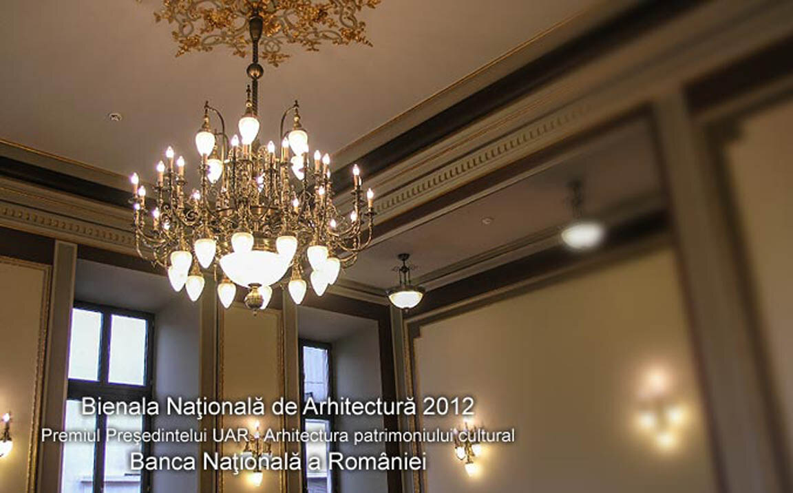 A boardroom in the Palace of the National Bank of Romania, with a large brass chandelier with opal shades, wall lights and a suspended ceiling fitting