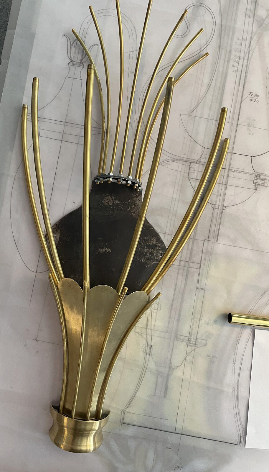 The brass structure of a sconce, placed over the technical drawing