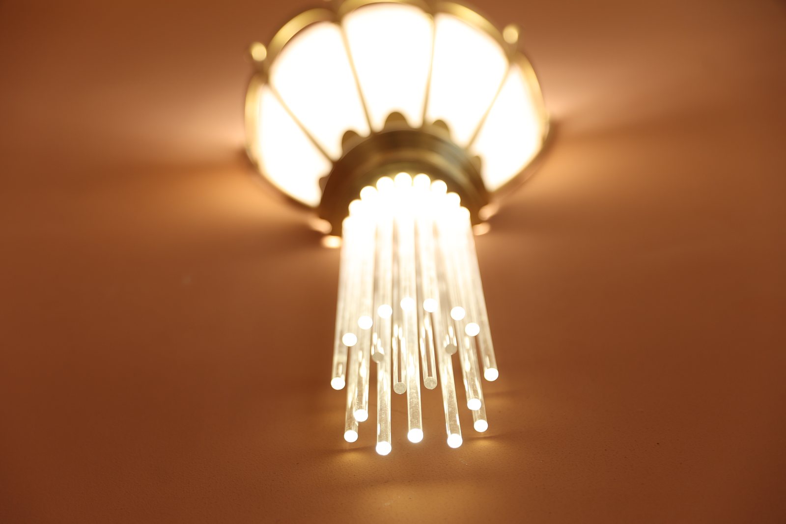 Detail of the lit glass rods beneath a brass sconce