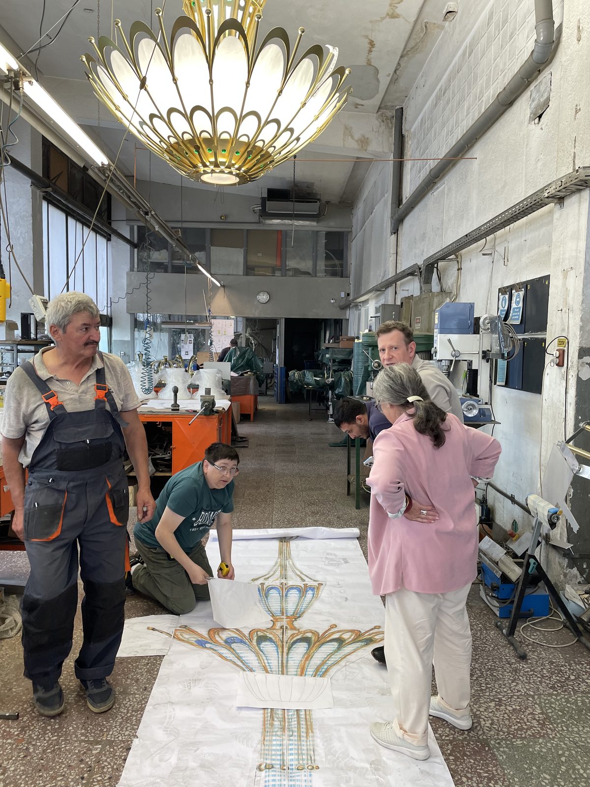 The workshop team around a full-scale drawing of the chandelier, laid on the floor