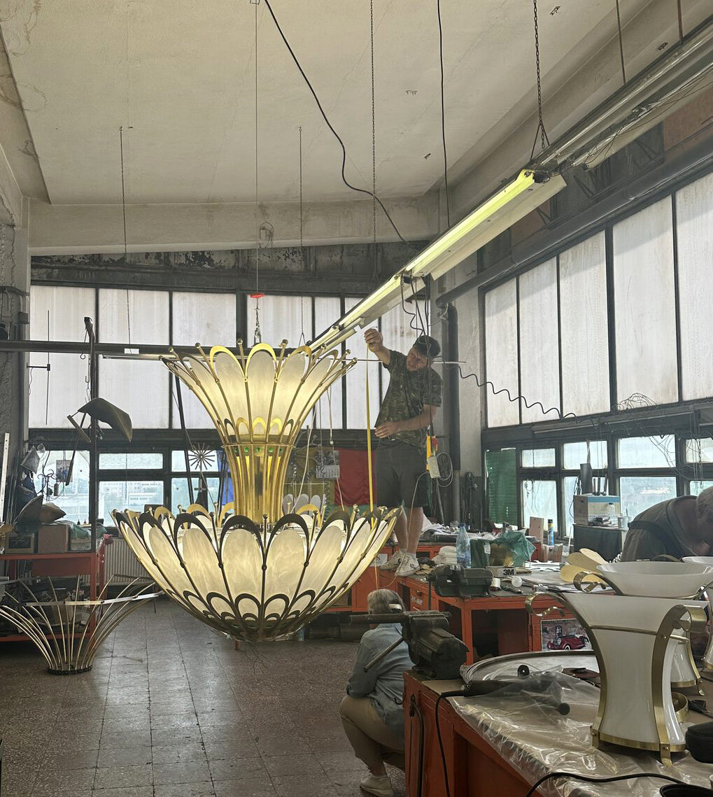 Two Art Nouveau chandeliers lit, suspended in the workshop