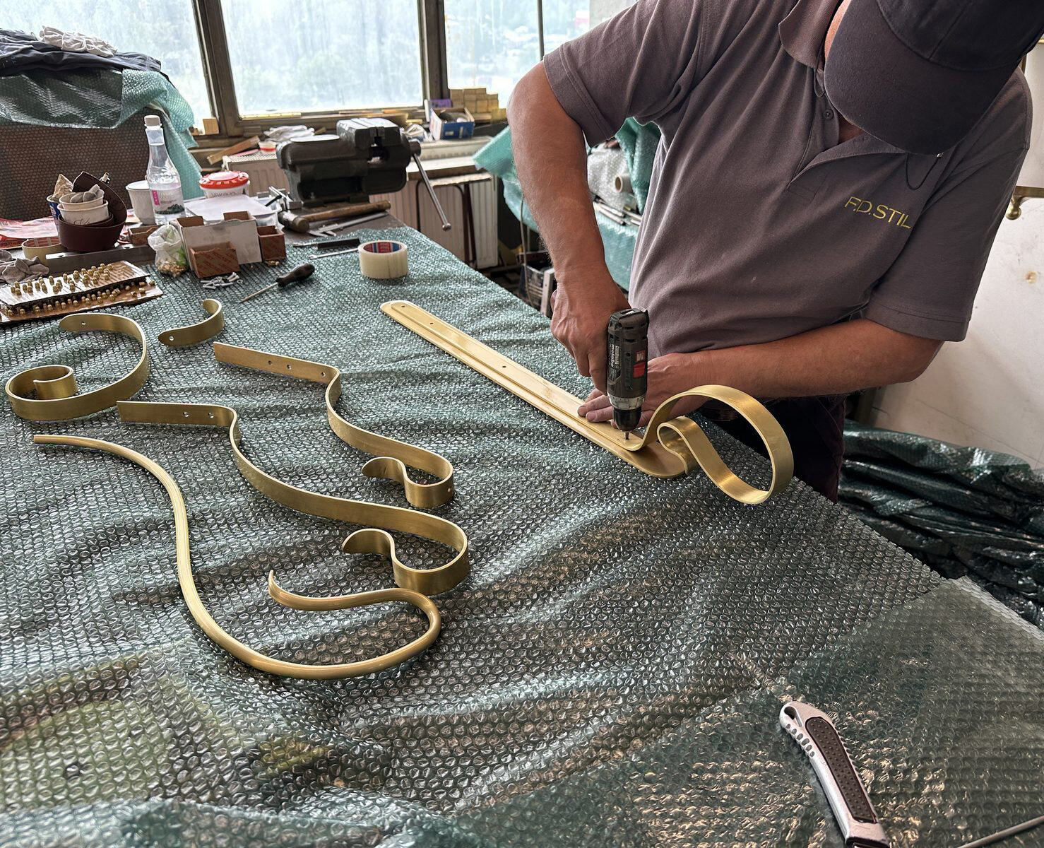 A craftsman bending a brass strip into a volute