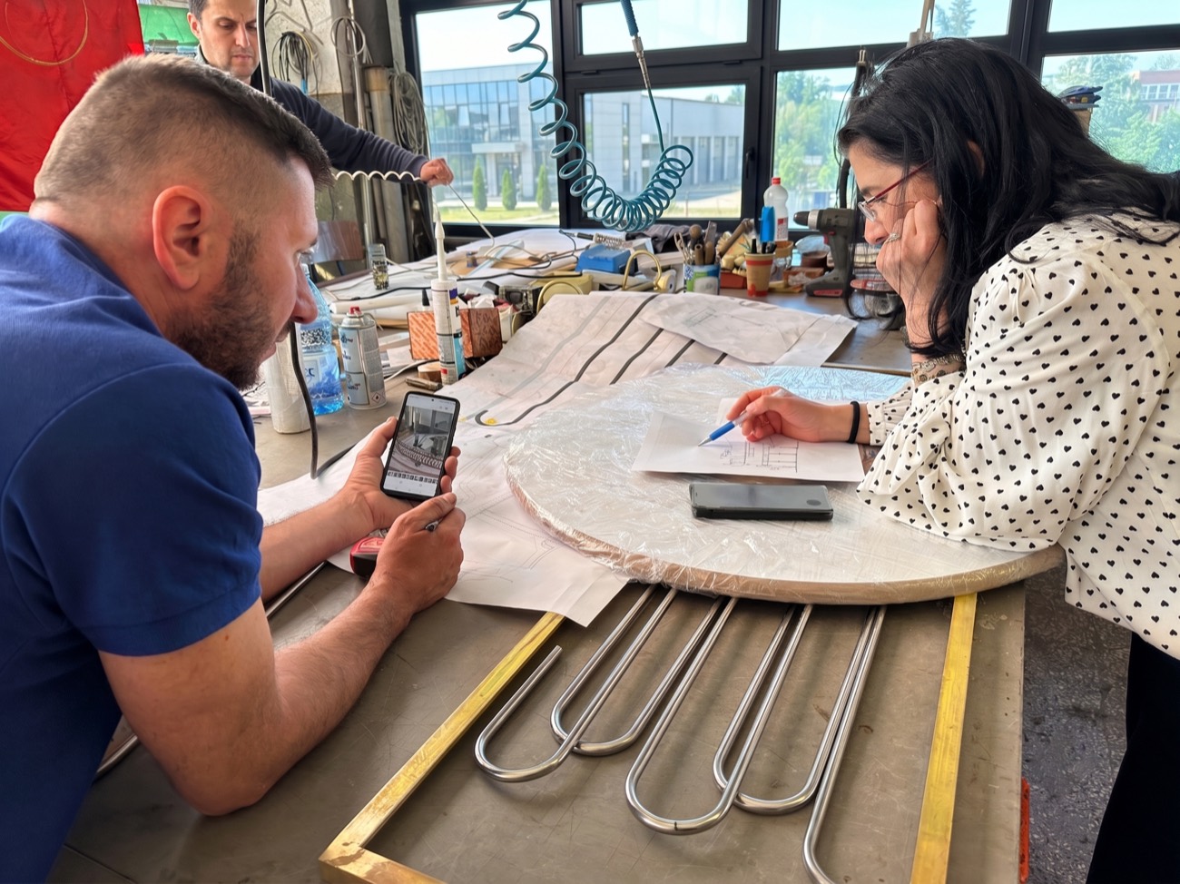 Designer and craftsman reviewing technical drawings at the workshop bench