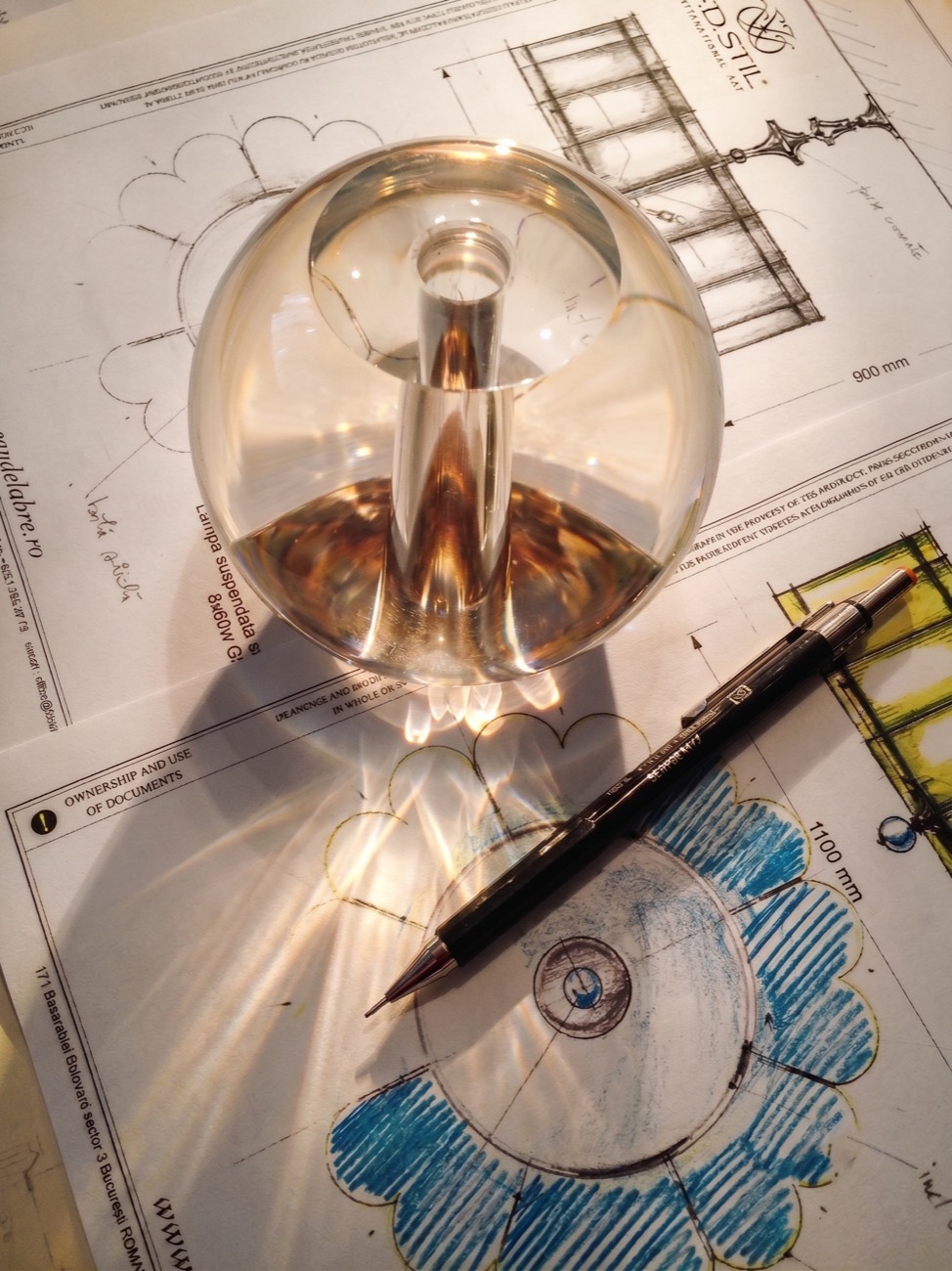 Crystal sphere resting on the technical drawings of a pendant lamp