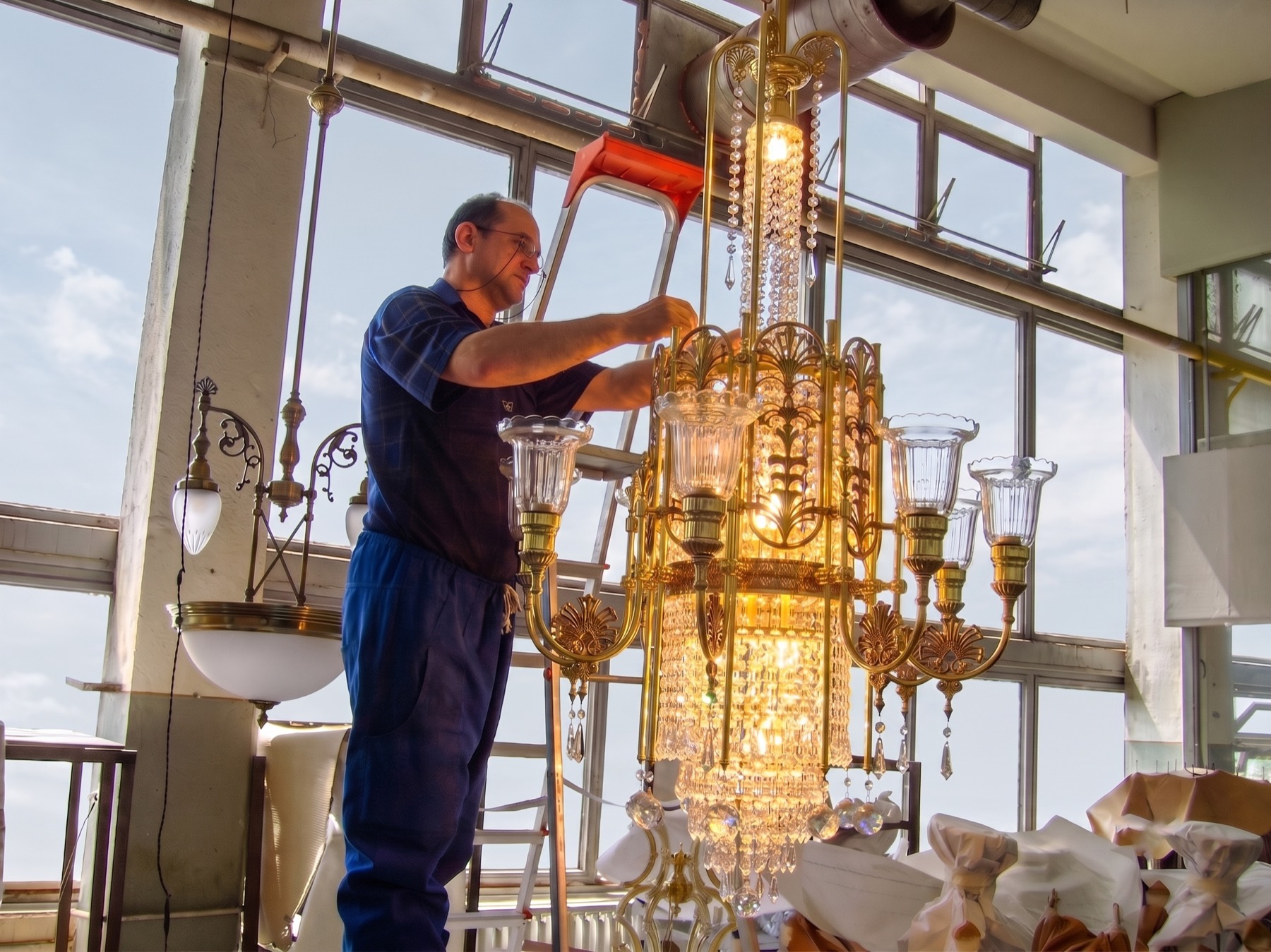 F.D. Stil craftsman finishing a gilded crystal chandelier in the workshop