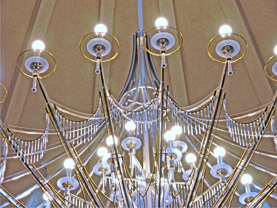 Detail of the stainless steel chandelier: brass rings around the sandblasted glass dishes and garlands of glass rods between the arms