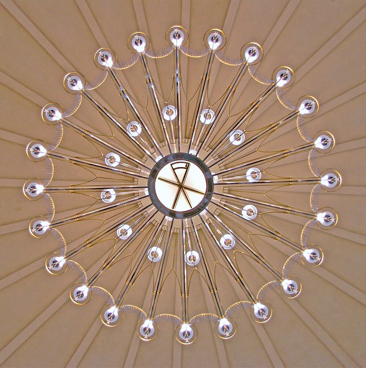 The Iași cathedral chandelier seen from directly below: a 24-arm rose laid over the ribs of the dome, with the monogram of Christ in the central lantern