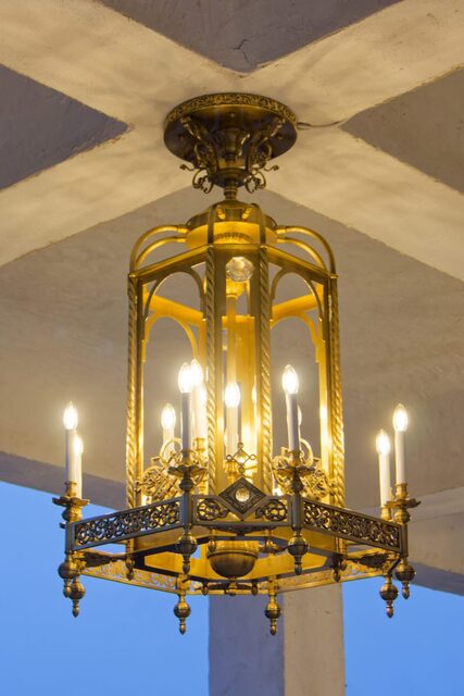 The monumental brass lantern in the porch of the church in Săpânța, lit at blue hour